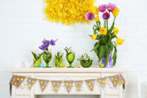 White fireplace with green vases and flowers on the mantel